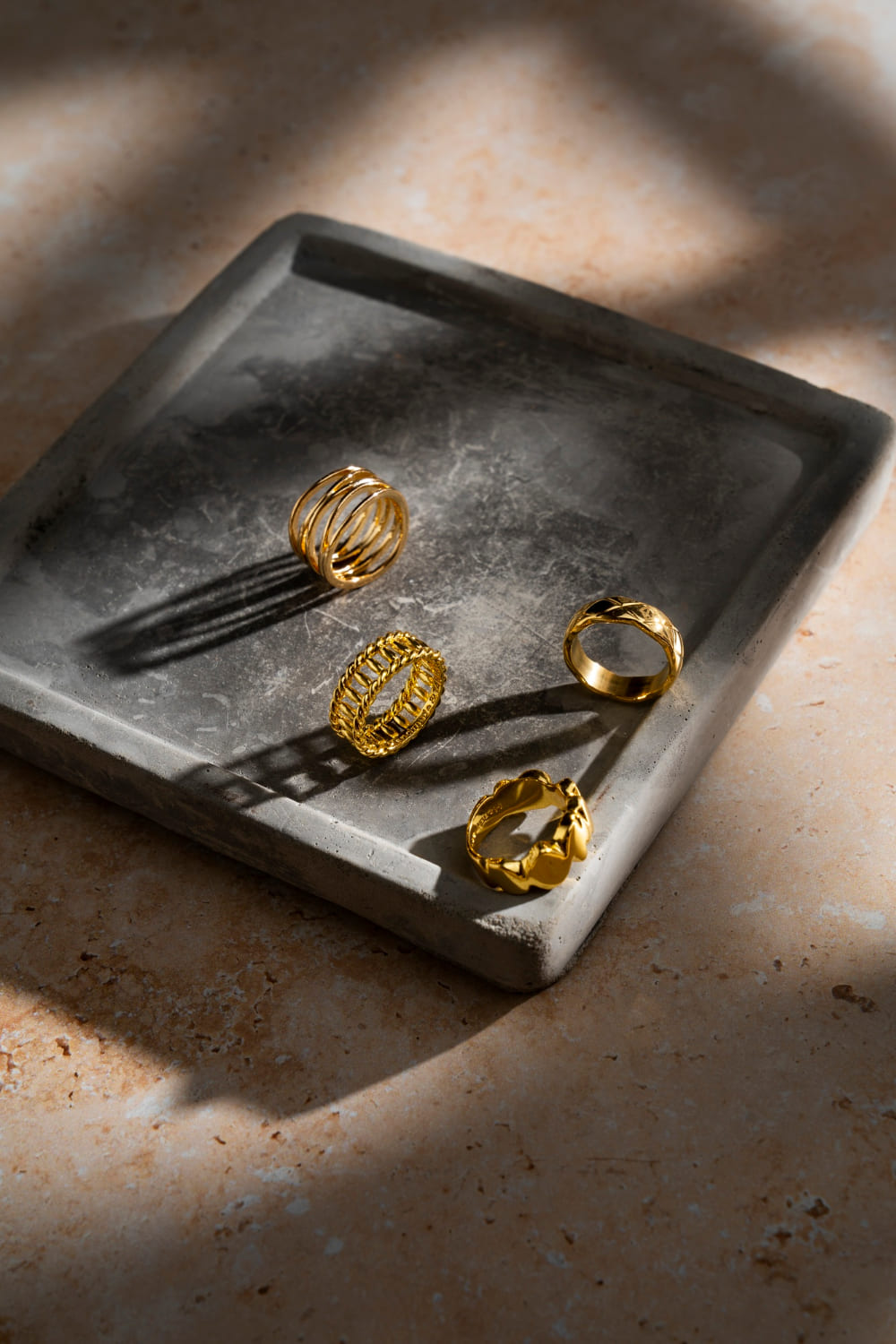 bandeja de semijoias cinza, quadrada, com anéis dourados em exposição